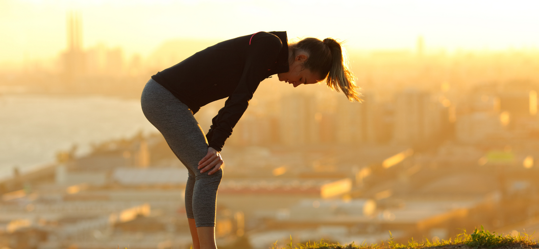 woman in jogging attire resting at a hilltop