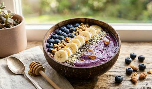 A vibrant purple blueberry smoothie bowl topped with fresh berries and a drizzle of Melora Manuka Honey.