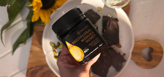 Jar of Melora Manuka honey being held over a table 